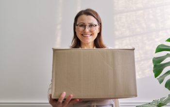 Woman with packaged package, cardboard box. Service for international postal delivery, auto delivery of goods, cargo. Female received purchases purchased in online stores